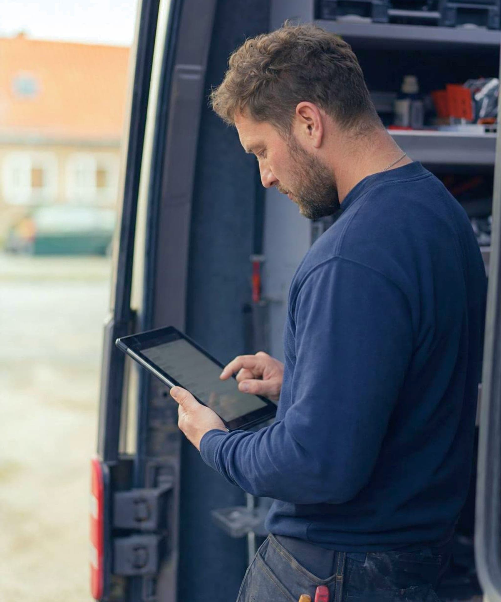VVS'er ved sin servicebil, i gang med at tjekke dagens opgaver på en tablet